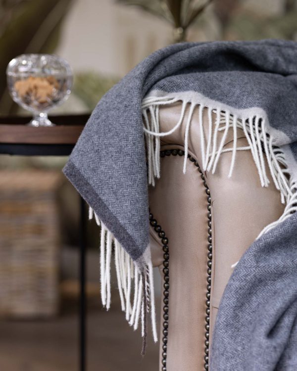 Grijze merino-kasjmier plaid Milano Grigio Orlo, elegant opgevouwen met zachte structuur en verfijnde afwerking.