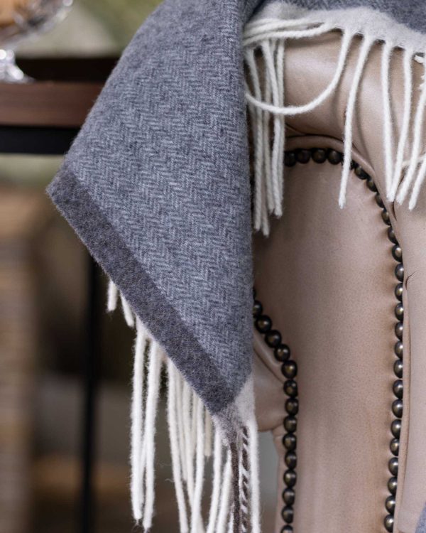 Grijze merino-kasjmier plaid Milano Grigio Orlo, elegant opgevouwen met zachte structuur en verfijnde afwerking.